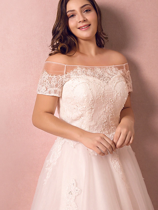 Close-up of the lace and pearl details on an off-shoulder wedding dress.