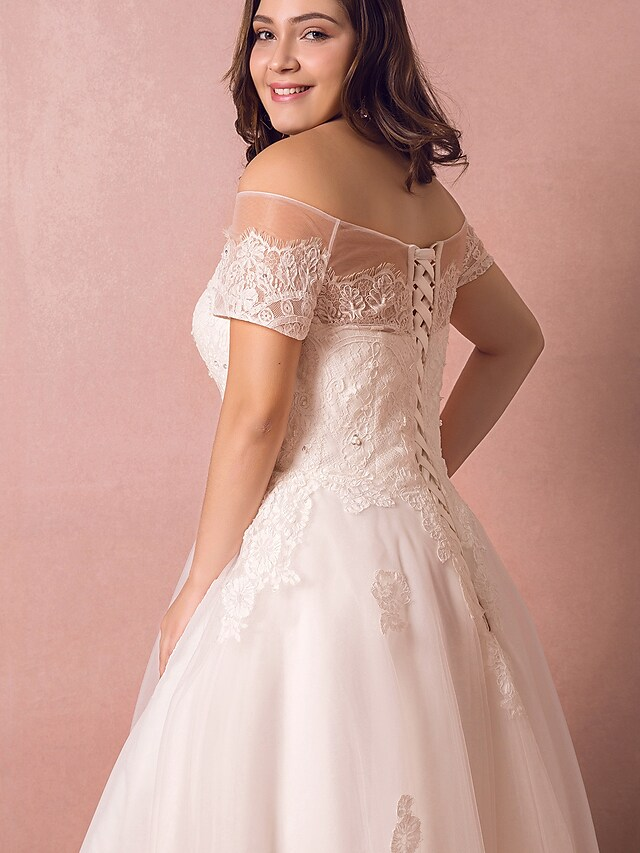 Side view of a bride wearing an A-line off-shoulder wedding gown.