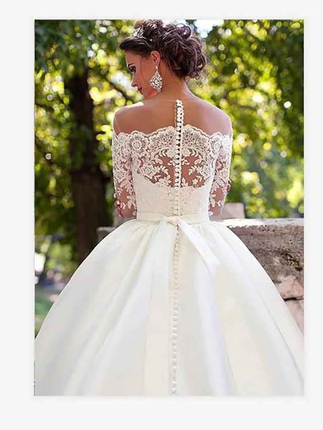 Close-up of the off-shoulder bodice and intricate lace illusion sleeves on the bridal gown.