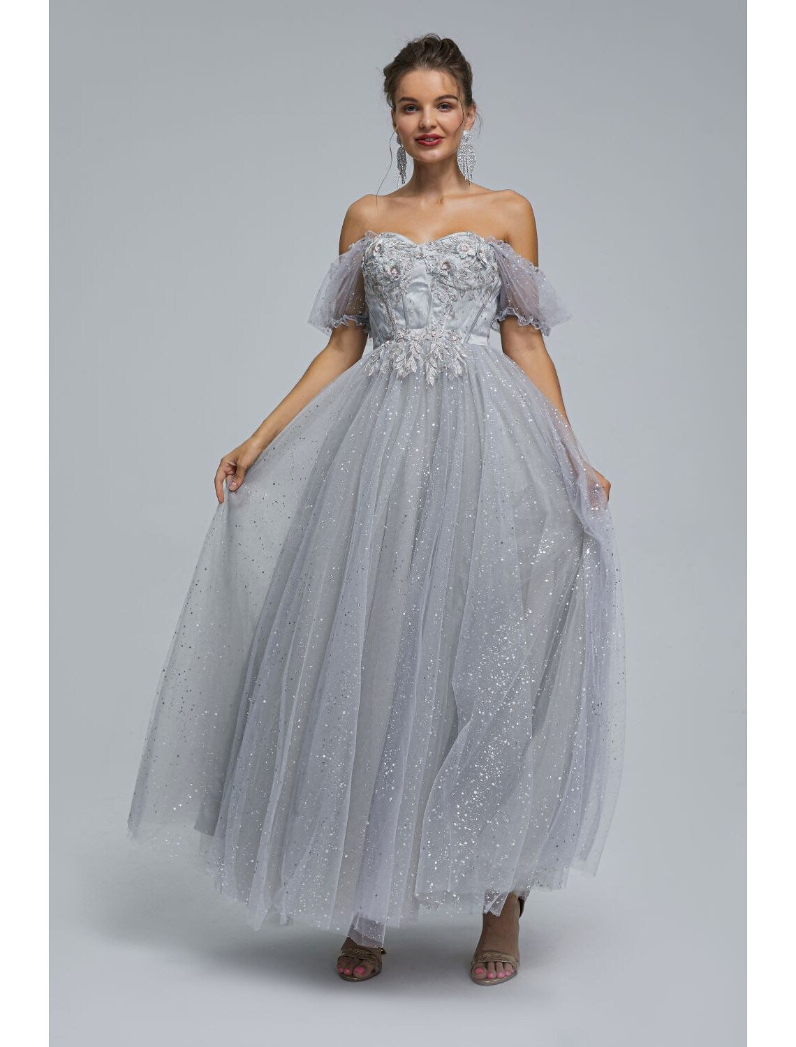 Model wearing an A-line off-shoulder tea length prom dress with sequin appliques.