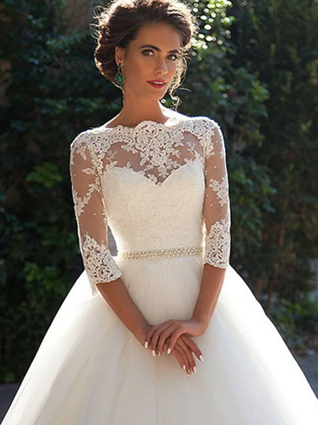 Close-up of delicate lace appliques and illusion sleeve detail on wedding dress.