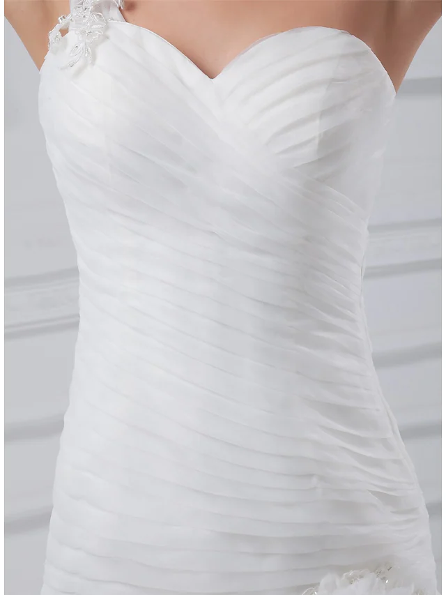 Close-up of ruched organza satin fabric and intricate appliques on the wedding dress.