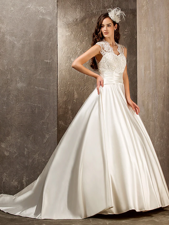 A-Line wedding dress with Queen Anne neckline, lace appliques, and satin sash.