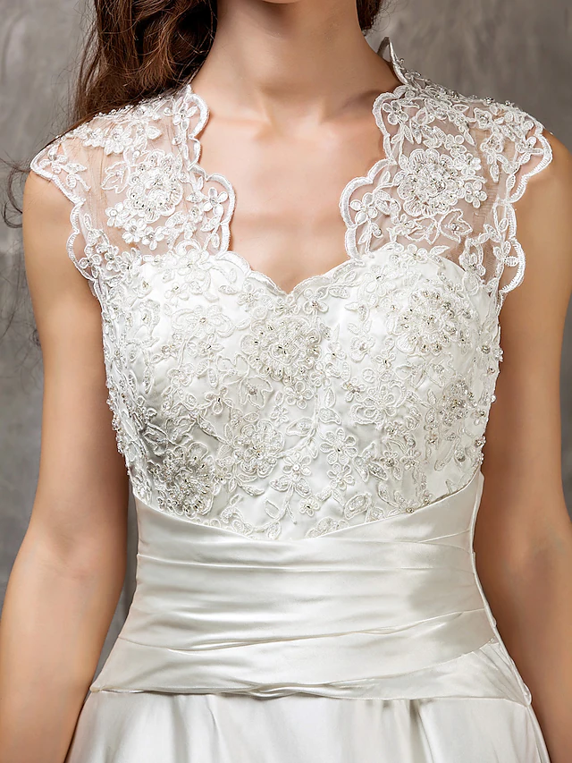 Detail of the satin sash and lace appliques on a wedding dress.