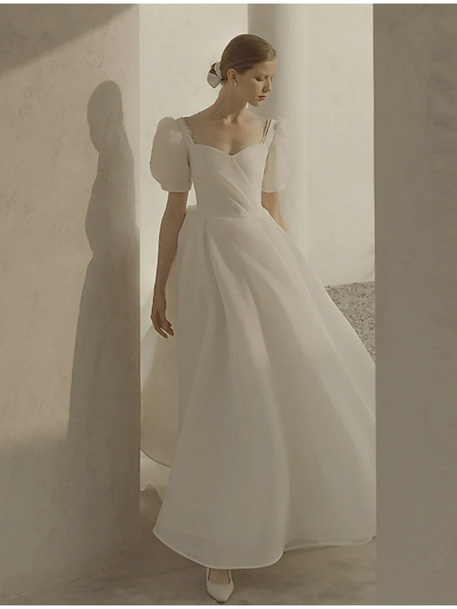 Front view of an A-Line scoop neck short sleeve white organza wedding dress with ruffles.