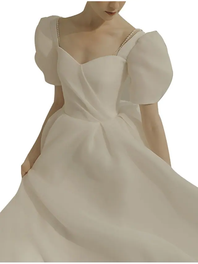 Close-up of the ruffled details on a white organza wedding dress.