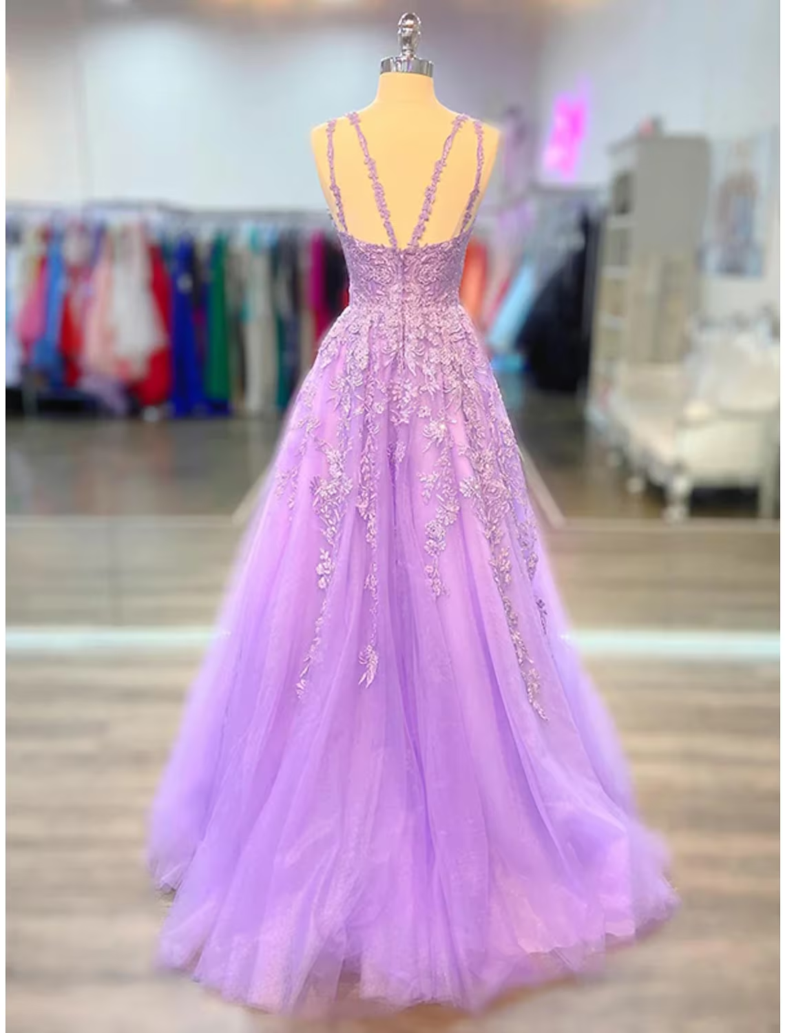 Back view of A-line prom dress showing court train and shoulder flower.