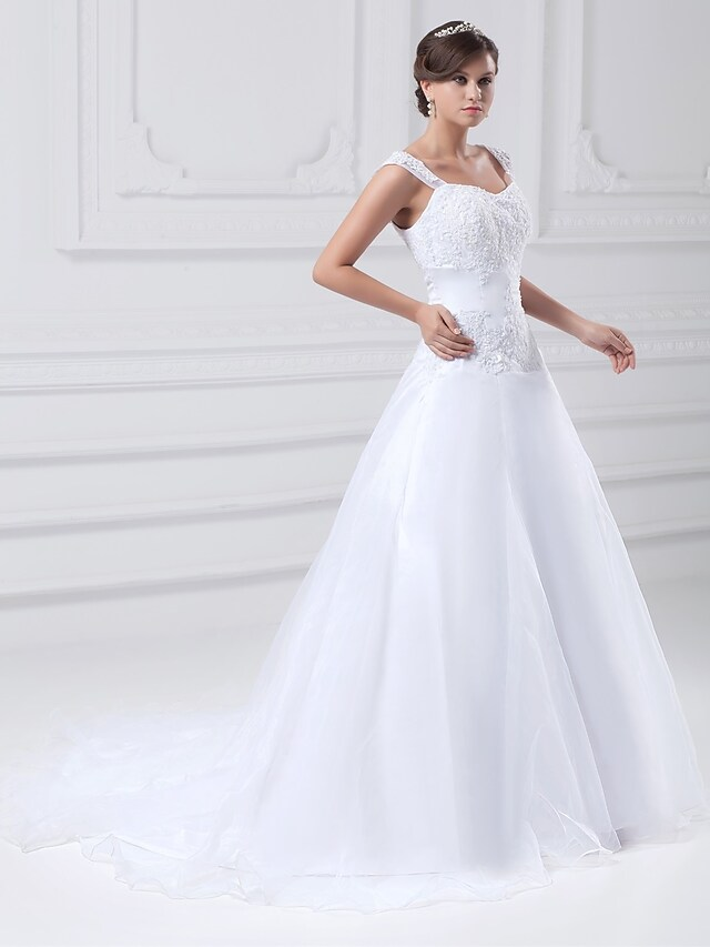 Close-up of lace and beading appliques on a white wedding dress.