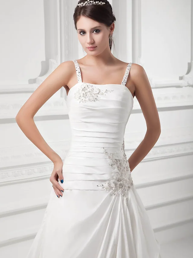 Back view of a wedding gown with a square neck, spaghetti straps, and flowing court train.