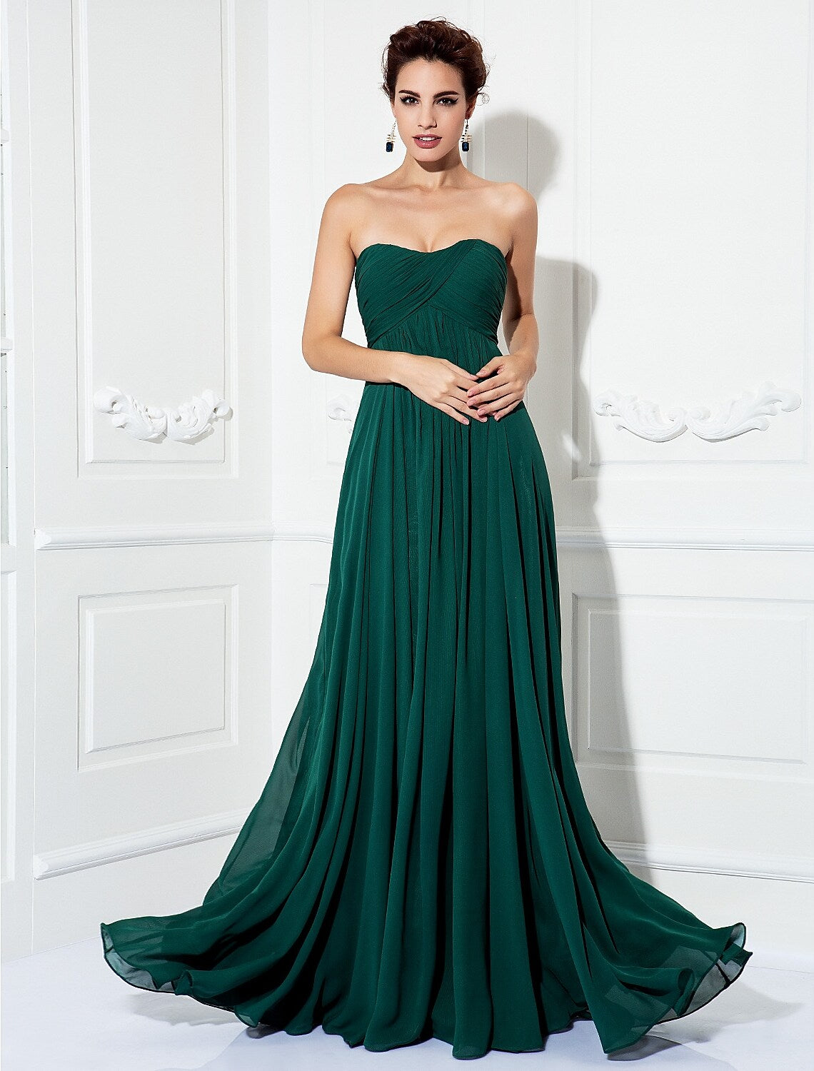 Full-length view of a woman wearing an A-line strapless chiffon dress with pleats and a sweep train.