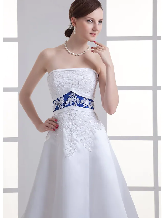 Full length view of a bride wearing an elegant strapless A-Line wedding dress.