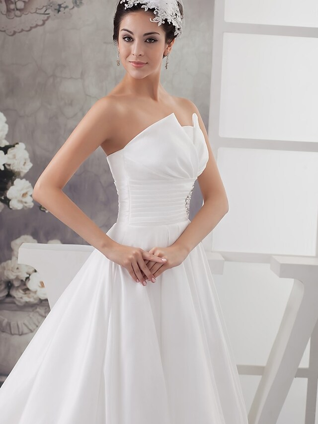 Close-up of ruched and beaded bodice on a satin wedding dress.