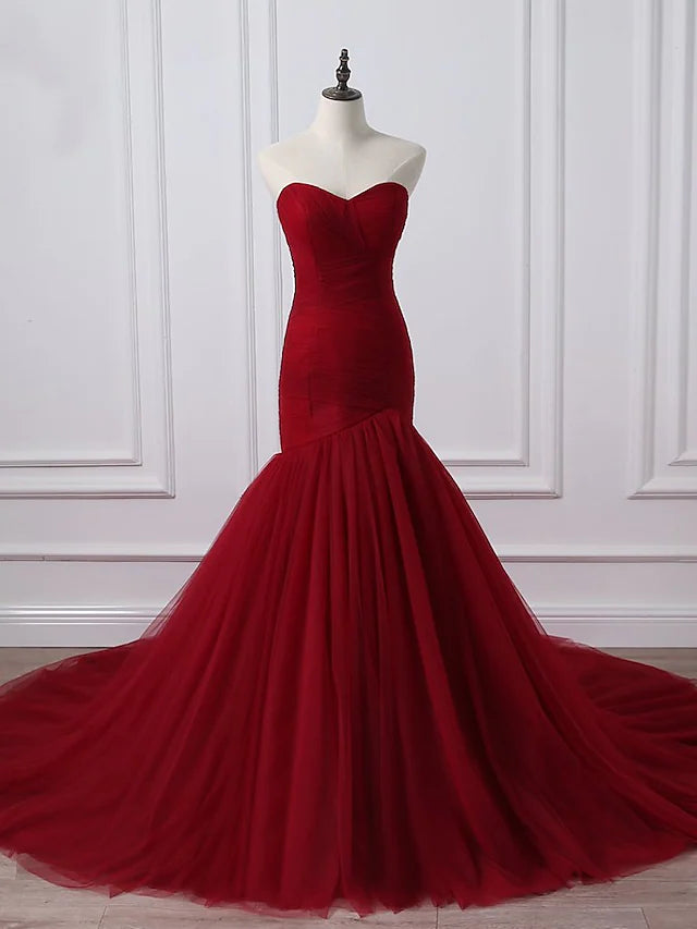 Plus size model wearing an elegant A-line strapless wedding dress with ruched bodice and chapel train.