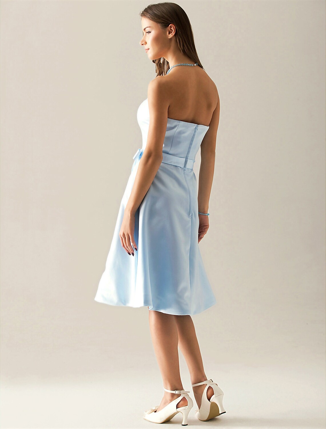 Back view of an A-line strapless satin bridesmaid dress with a sash, worn by a model.