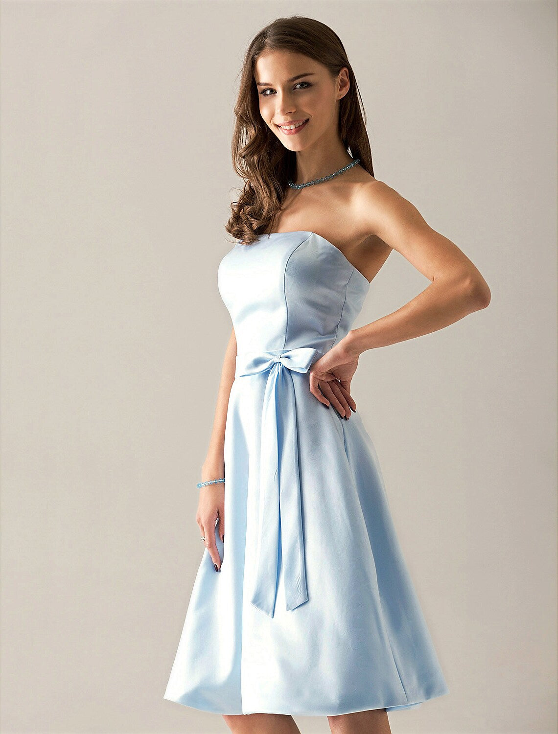 Side view of an A-line strapless satin bridesmaid dress, showing the knee-length hem.