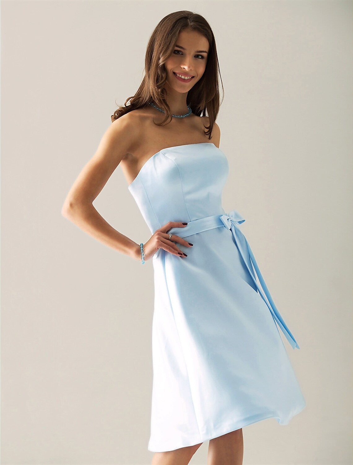 Model posing in an A-line strapless satin bridesmaid dress, showcasing its elegant drape.