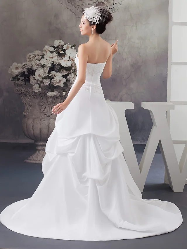 Close-up of beading appliques on strapless satin wedding dress.