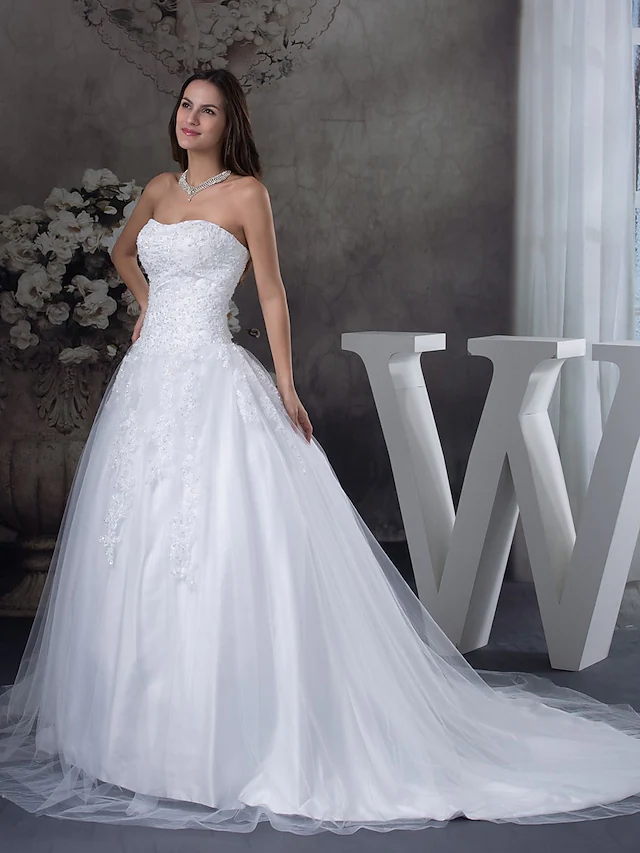 Side view of an A-line wedding dress showcasing lace appliques and court train.