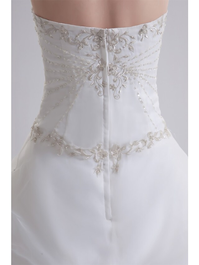 Detail of ruched fabric and beading on strapless wedding dress.
