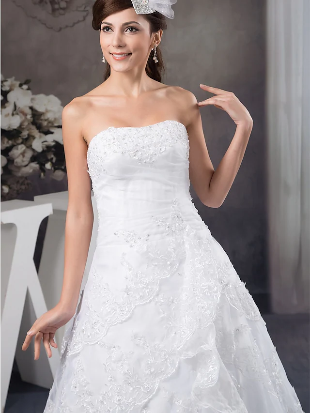 Side view of a bride wearing an A-Line strapless wedding gown.
