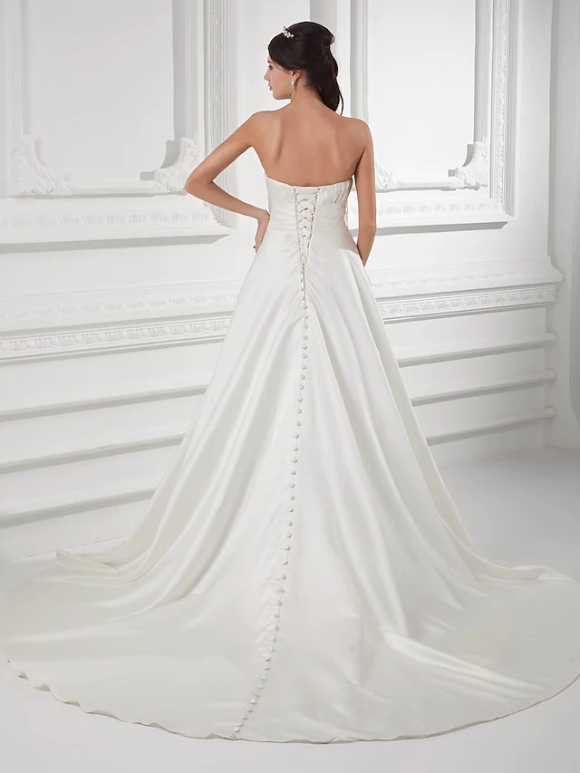 Close-up of ruched satin fabric and beading on wedding dress.