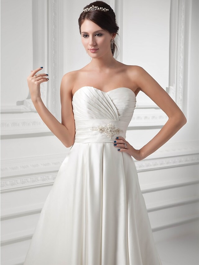 Side view of strapless A-Line wedding gown with flowing court train.