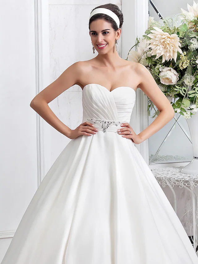 Back view of the satin wedding dress showcasing the sash and beading.