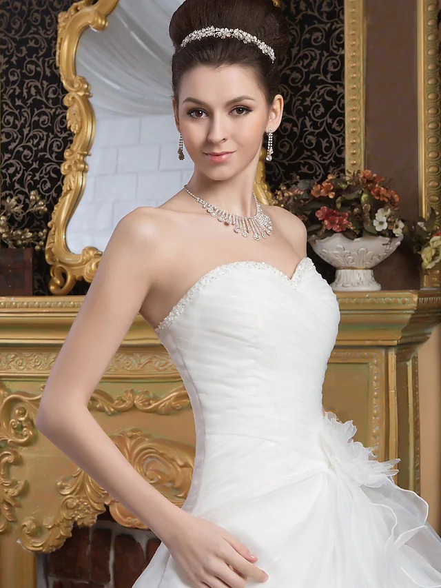 Full length view of a bride wearing a strapless A-line wedding dress with a flowing court train.