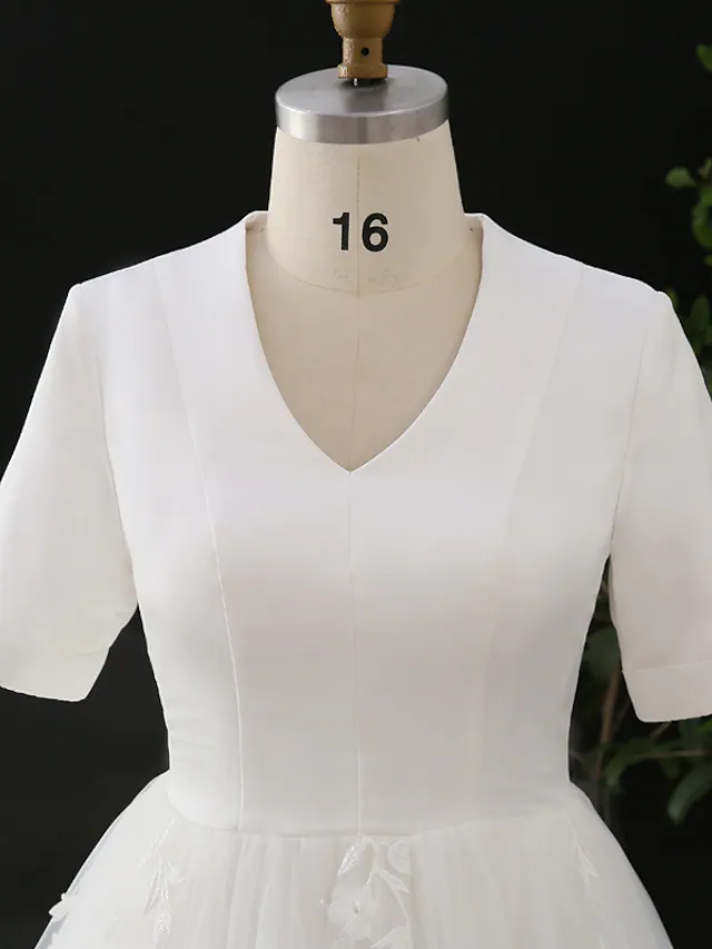 Detail of the appliques on the satin and tulle fabric of the wedding dress.