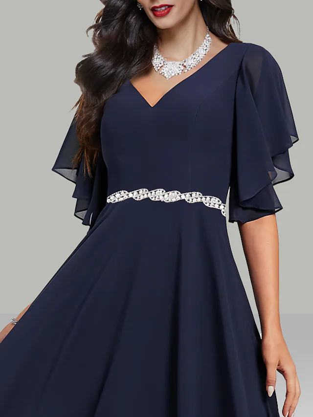 Close-up of the V-neckline and short sleeves of the chiffon dress, showing rhinestone details.