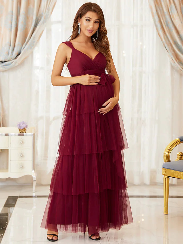 Woman wearing an elegant A-line V-neck sleeveless tiered tulle maternity evening dress.