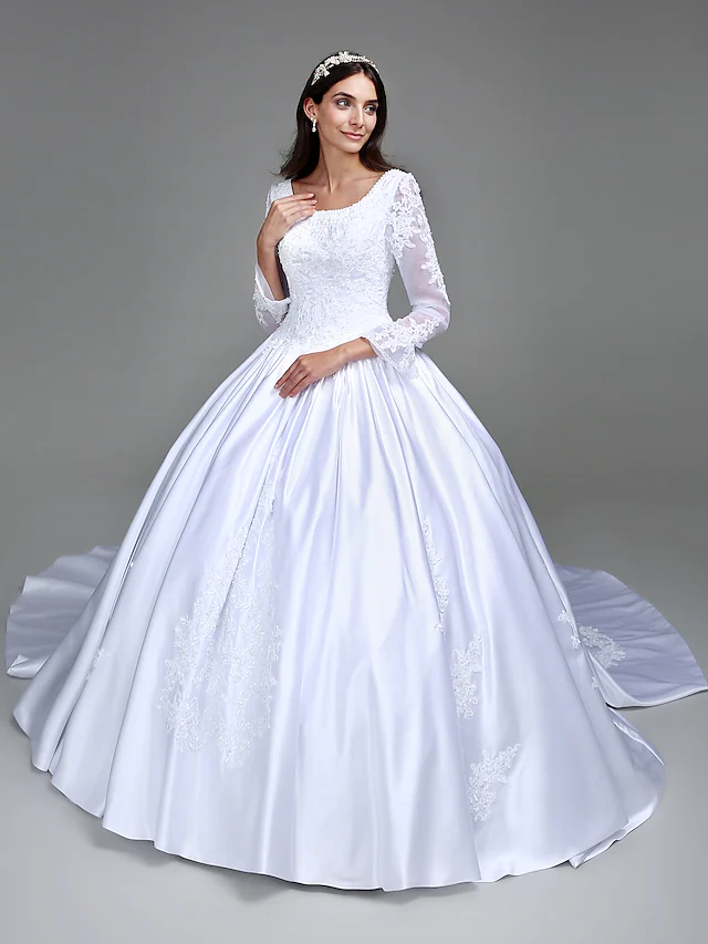 Model wearing an elegant vintage ball gown wedding dress with a scoop neck and long sleeves.