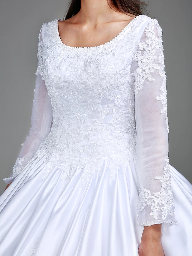 Bridal model posing in a long sleeve satin wedding dress with vintage details.