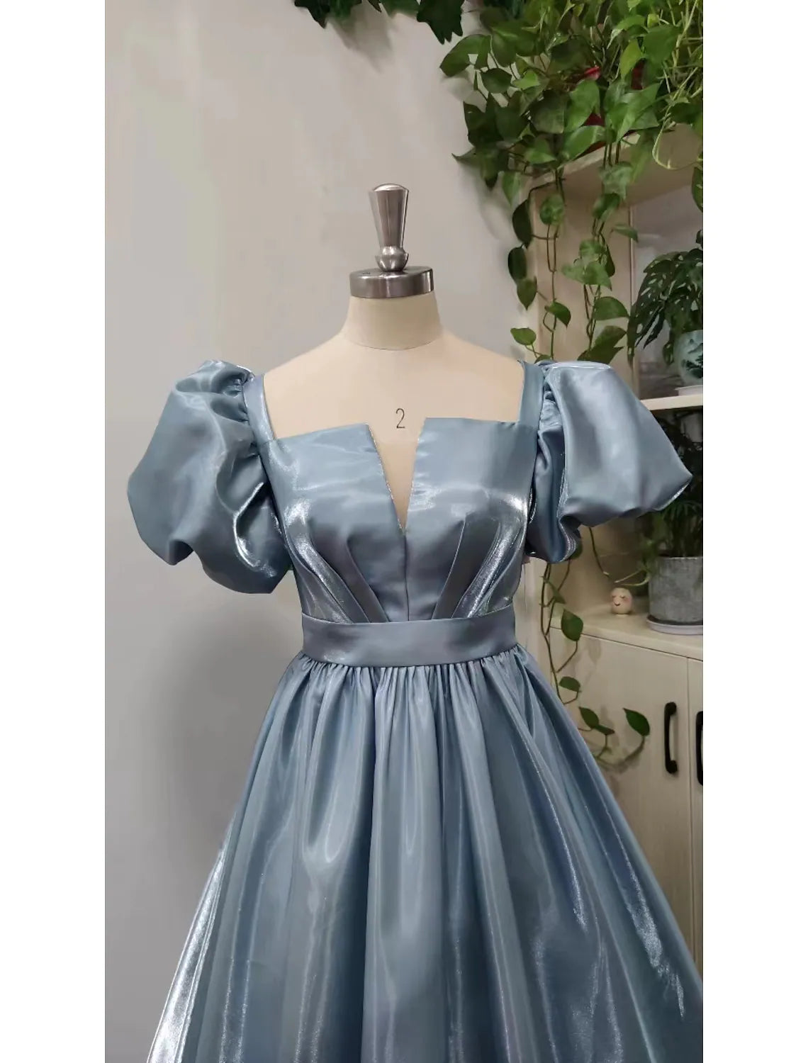 Back view of an elegant quinceanera ball gown in satin, showing the floor-length skirt.