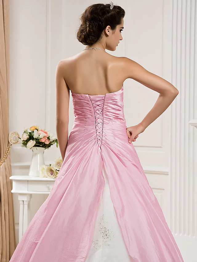 Full length view of a white strapless wedding dress with a voluminous skirt.
