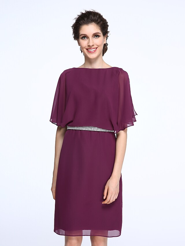 Woman posing in the knee-length Mother of the Bride dress, highlighting its silhouette.