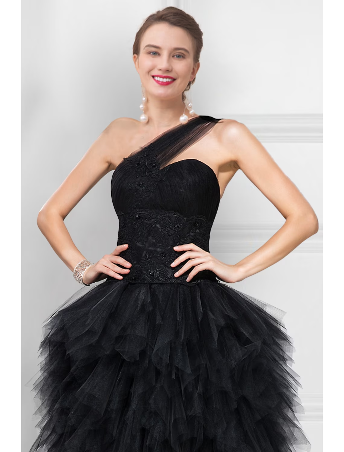 Side view of a black asymmetrical ball gown with a flowing tulle skirt.