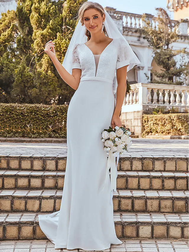 Side view of a bride wearing a draped chiffon trumpet wedding gown.
