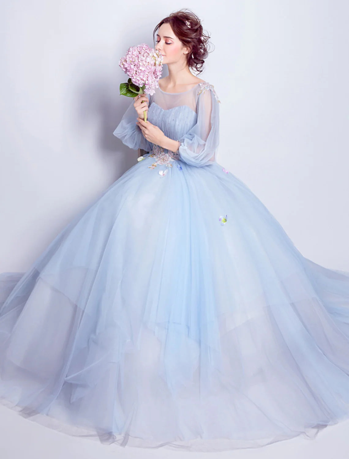 Model wearing elegant floral puffy ball gown with illusion neck and 3/4 sleeves.