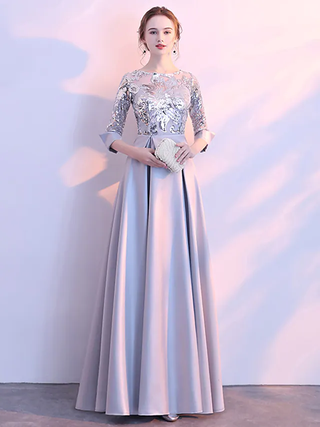 Elegant A-line glittering evening dress with jewel neck and 3/4 sleeves.
