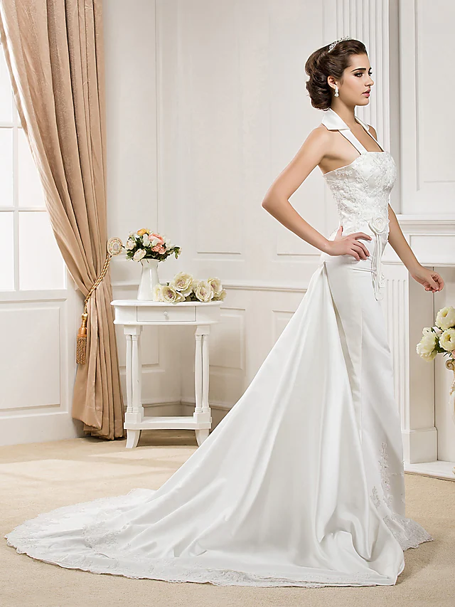 Side view of a bride in a white halter neck mermaid wedding dress, showcasing the train.