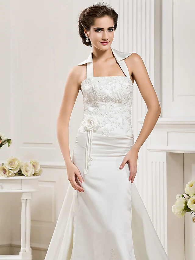 Bride posing gracefully in a white satin mermaid wedding dress.