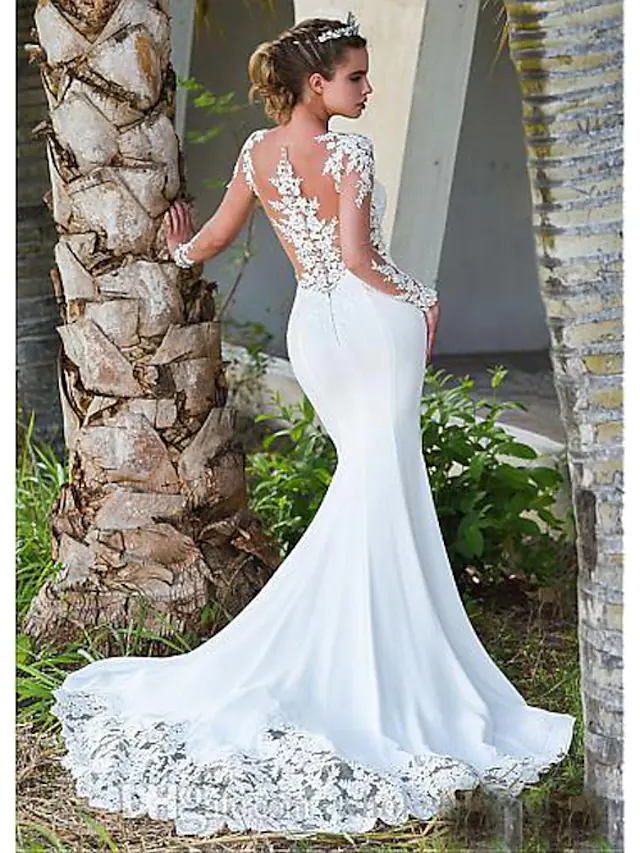 A bride in an elegant white mermaid wedding dress with a jewel neck and long lace illusion sleeves, featuring a court train.