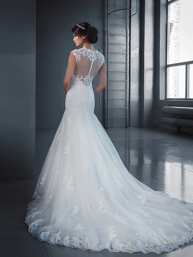 Back view of a white mermaid wedding dress featuring lace appliques and a flowing court train.