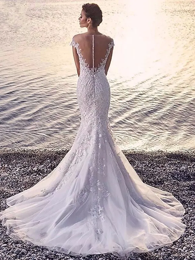 Close-up of the white organza wedding dress showing appliques and court train detail.
