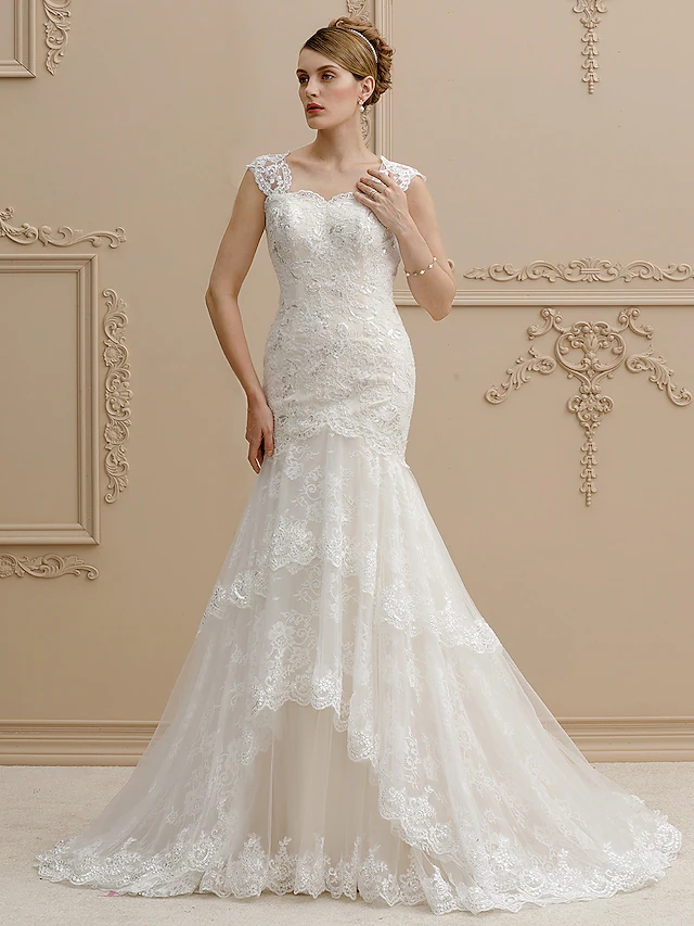 Woman wearing an elegant mermaid wedding dress with a square neckline and lace details.