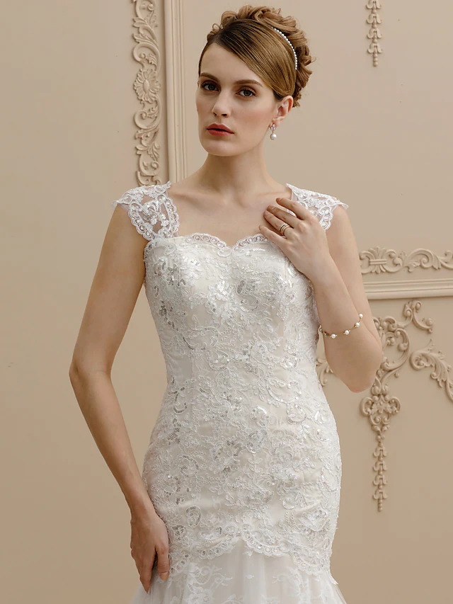 Side profile of a bride in a mermaid wedding dress with a flowing court train.