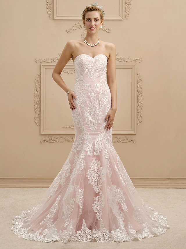 Front view of a sweetheart strapless mermaid wedding dress with lace appliques and court train.