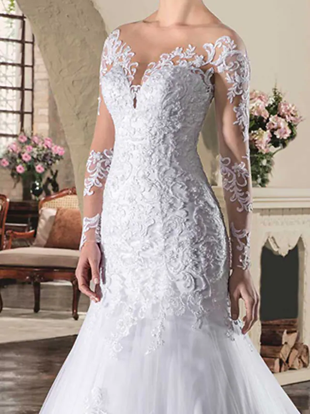 Close-up of intricate lace appliques on the long illusion sleeve of the bridal gown.