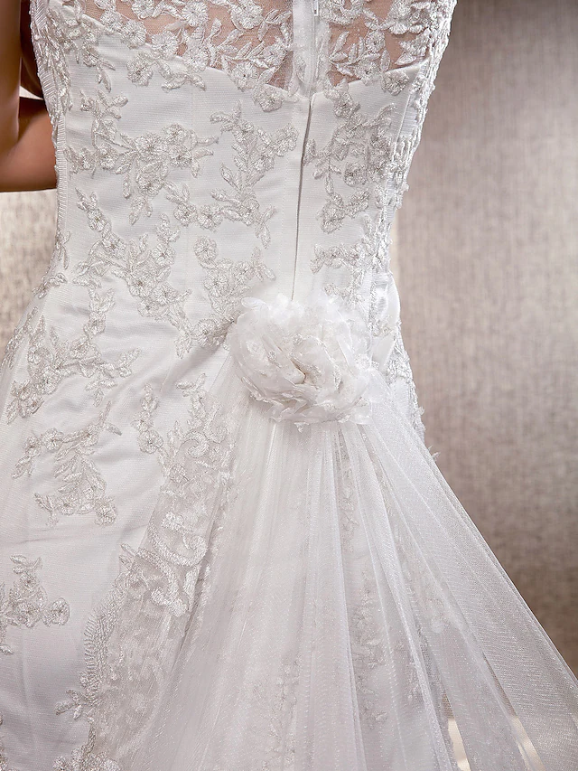 Detailed view of the scoop neckline and sleeveless design of the wedding dress.